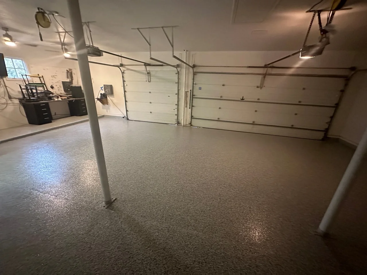 A cleared garage with 2 doors, a workbench and an open floor