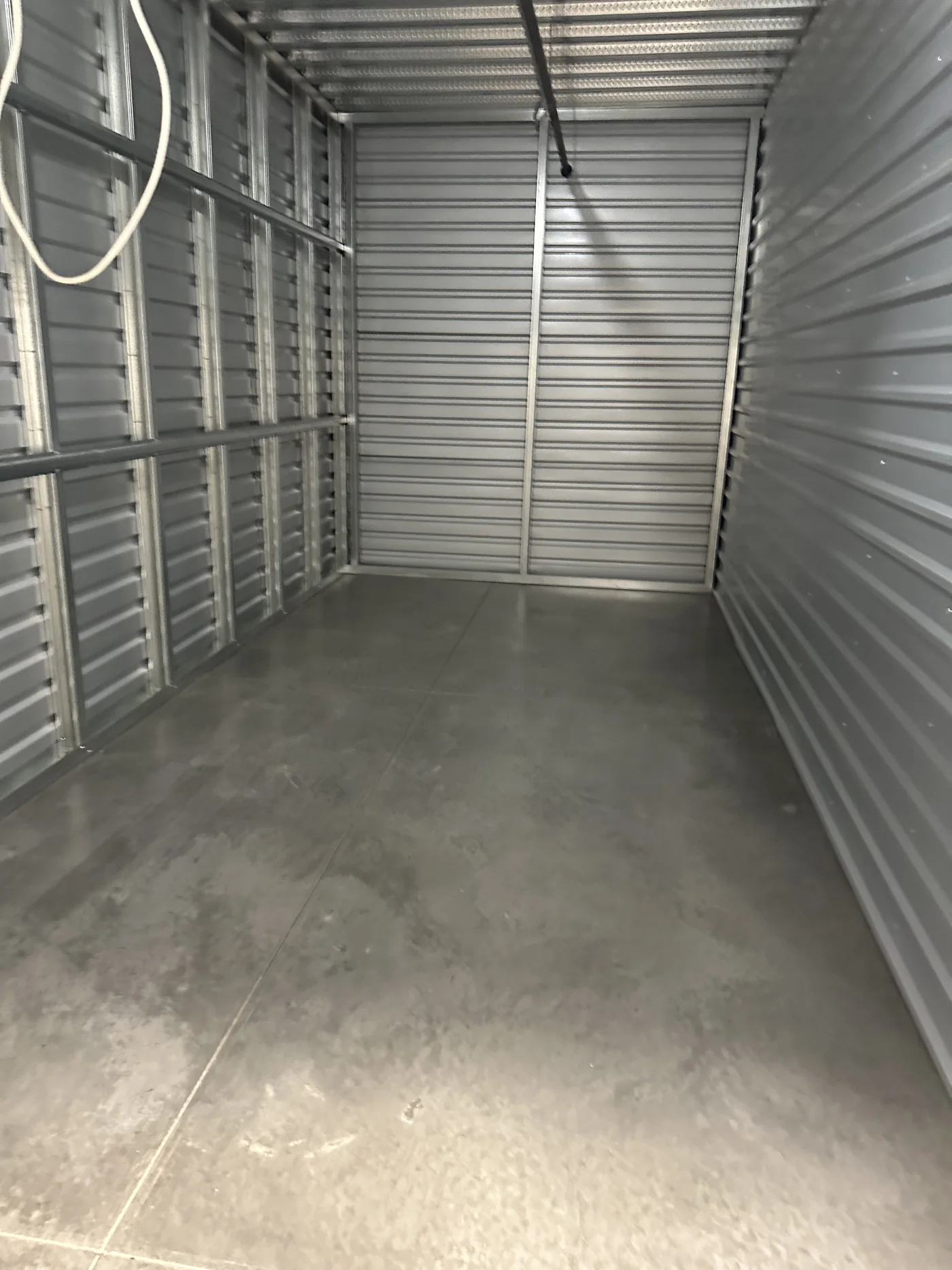 An empty storage unit with metal walls and a clear concrete floor