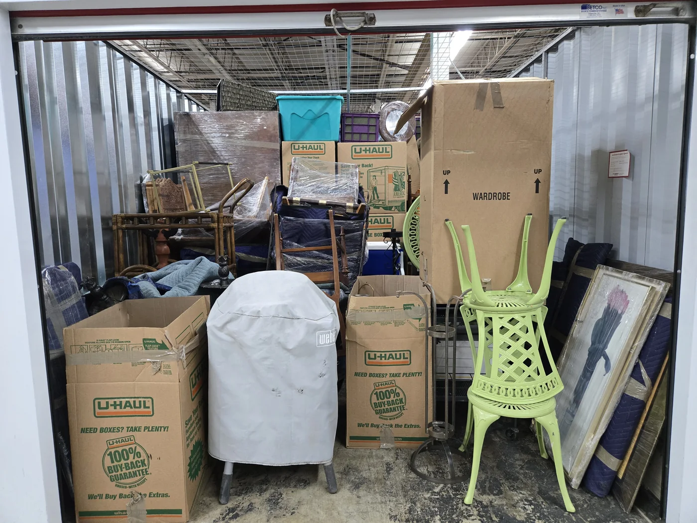 Furniture protected with moving blankets and wrap, with boxes in a storage unit