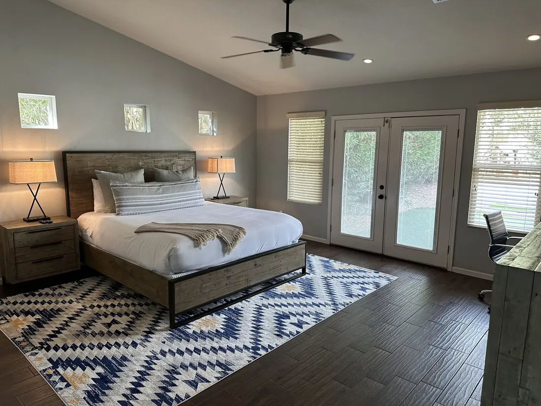 A made bedroom with french doors opening onto the yard
