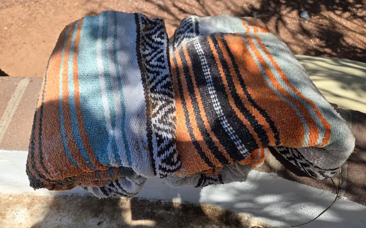 Worn striped blankets stacked on a low wall after
being sorted out of a back yard